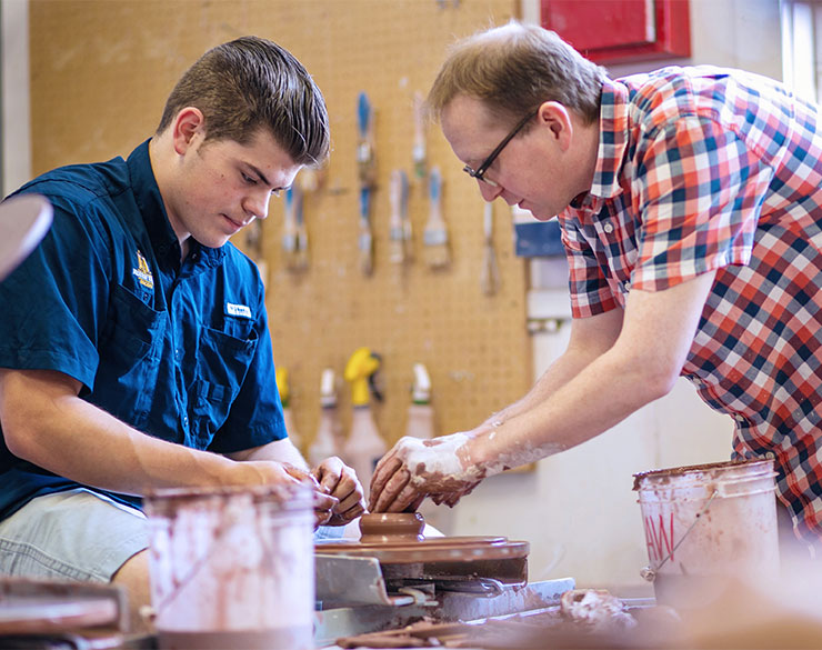 Ceramics student works with faculty