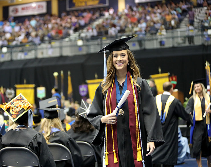 A woman smiles at commencement