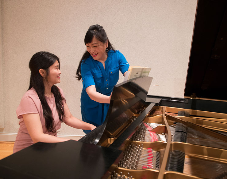 Professor helps student with piano performance