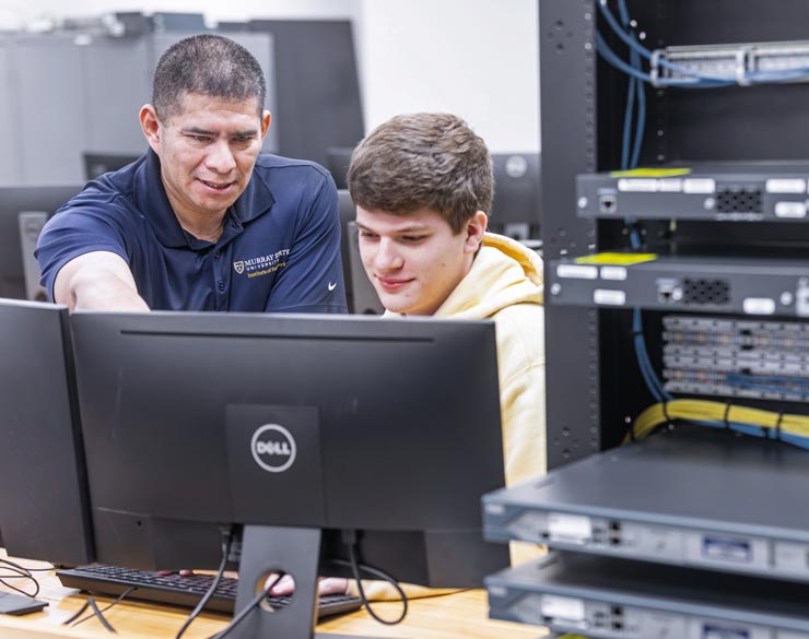 Faculty member helps student at computer