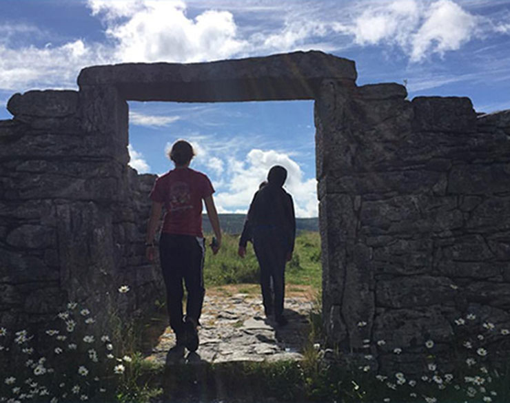 Two students walk through a stone gate