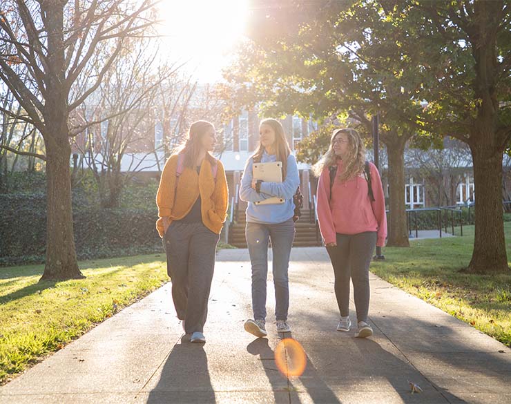 Three students walk on the Henderson campus