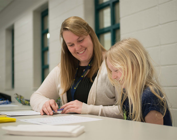 Teacher helps young student with worksheet