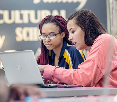 Two students work at a laptop