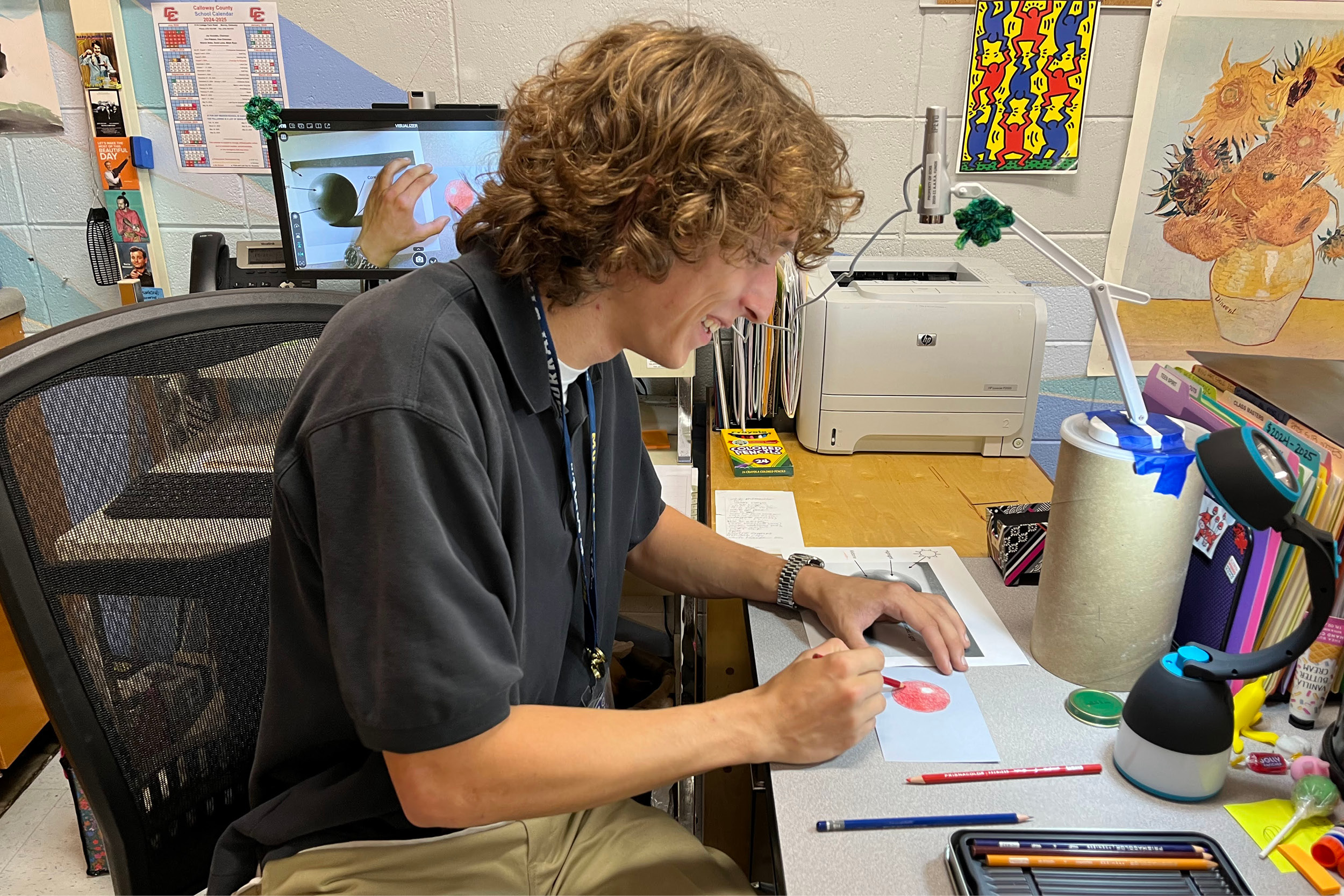 An art education student draws a 3D sphere using colored pencils.