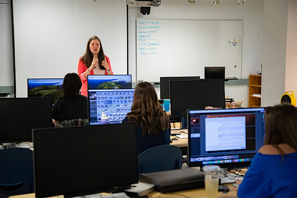 Professor Cintia Segovia Figueroa teaches photography students how to operate computer software.