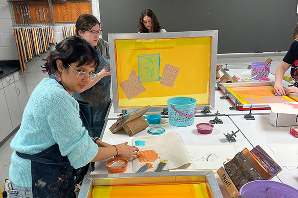 Printmaking students work with silkscreen presses.