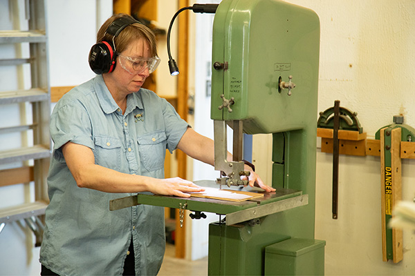 Professor Sarah Martin demonstrates how to use a saw. 