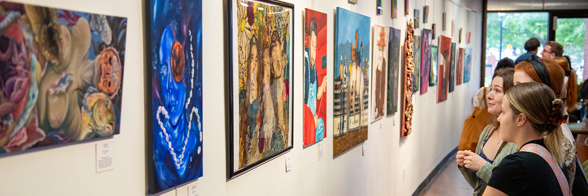 Students look at a gallery wall filled with student art.