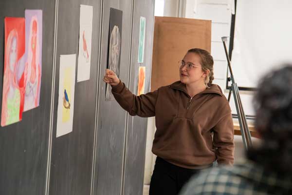 a student presents drawings displayed on board during critique