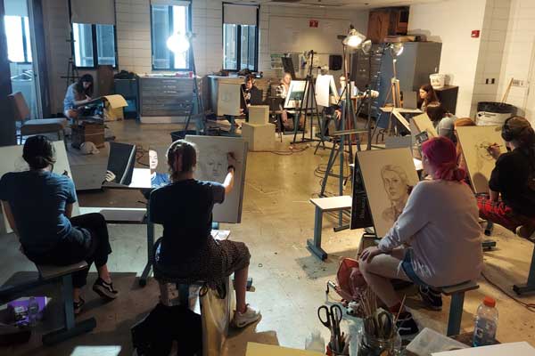 students with easels practice their drawing skills during class