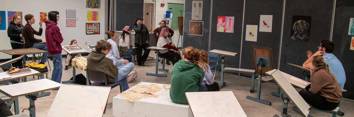 students in an art class listen to a lecture