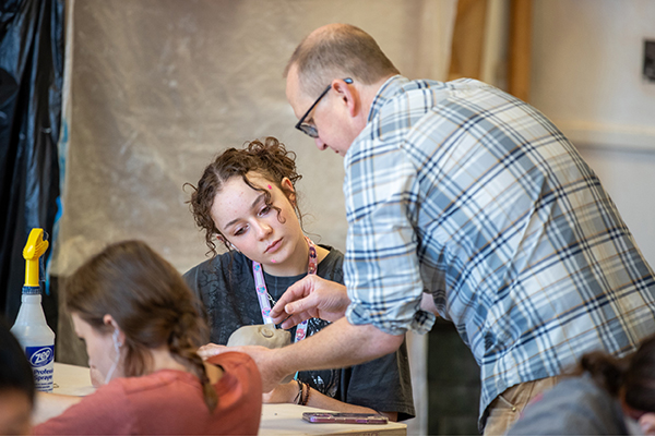 Professor John Utgaard helps a SAW student with her ceramics project.