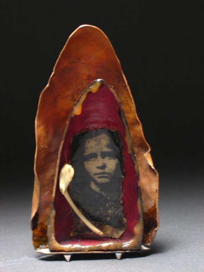 A metal sculpture with two layers and an old photo embedded at the center. 