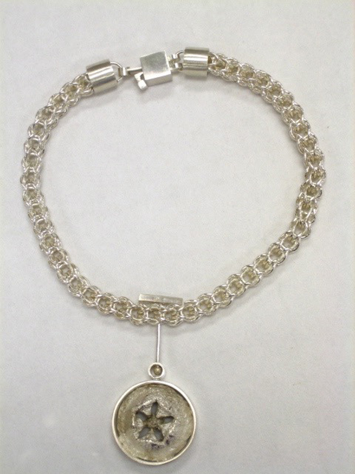 A handcrafted necklace with a sand dollar design. 