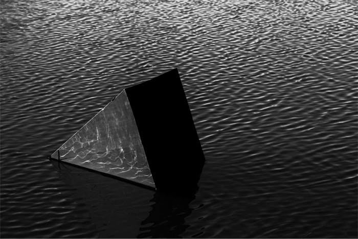 A photo by student Connor Wolfe of a reflective pyramid sitting in a body of water. 