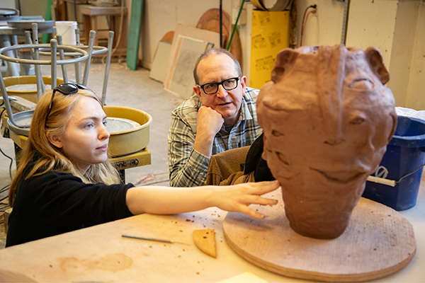 Professor John Utgaard offers pottery advice to a ceramics student.