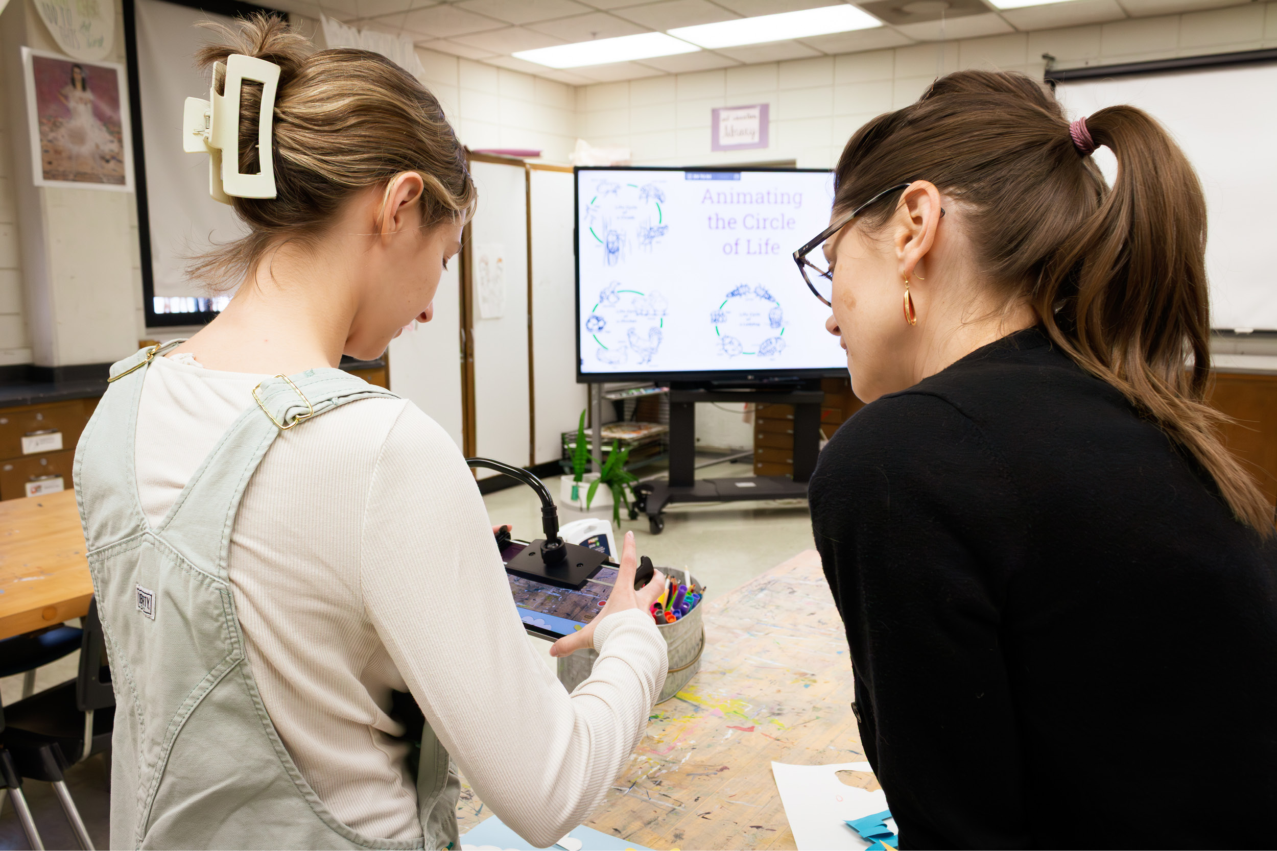 Two art education students follow along with a papercrafting video tutorial.
