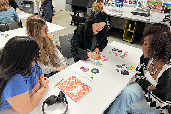 A group of graphic design students shares their illustrations and feedback with each other. 