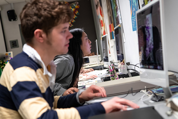 Two graphic designers work on their projects in the design studio.