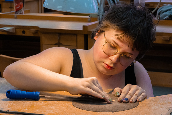 A metalsmithing student intently works on their project.
