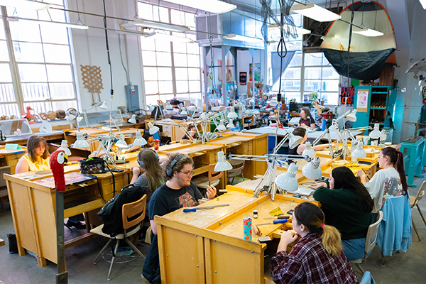 Overview of the metalsmithing studio space. In this large workspace, students work at individual workbenches with personal toolkits and lamps. 