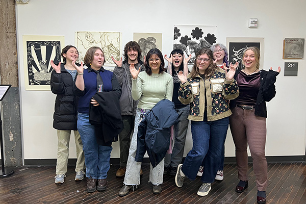 Murray State printmaking students raise their shoes up as they show off their work. 