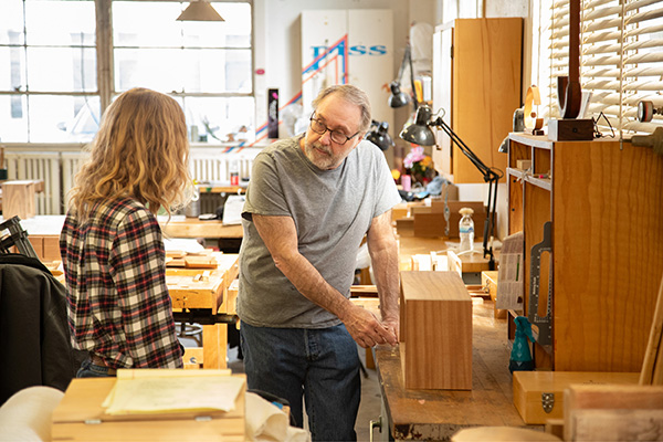 One woodworking student discusses his project with another.