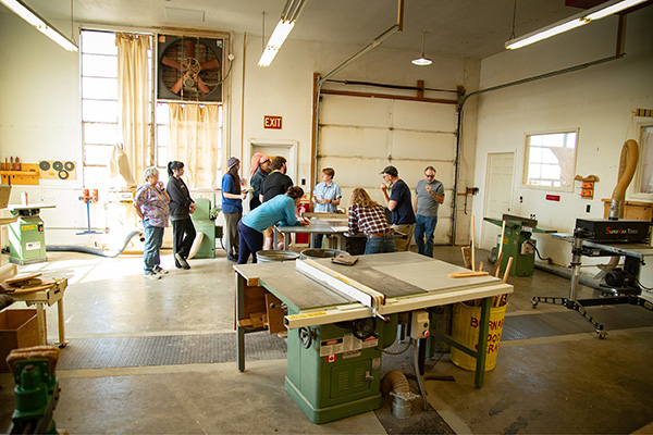 Alternate angle of the woodworking studio. From this angle, you can see more of the cutting tools and a garage door.