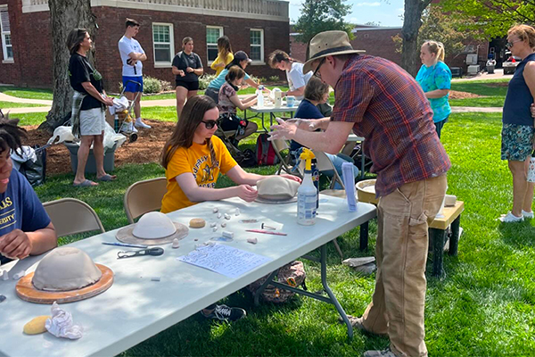 Clay Club students sit outside at tables and make ceramic bowls for passersby as part of the Empty Bowls Project, in collaboration with the Murray Art Guild. 