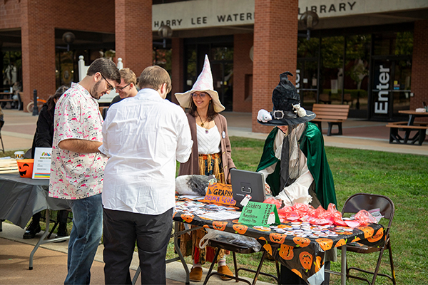 Two students dressed as witches sell their artwork to passersby as part of the Monster Mash fundraiser event. 
