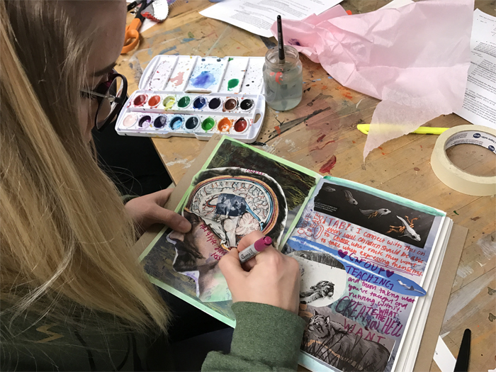 A student writes in her art journal. 