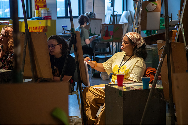 A spotlight shines on a SAW student as she works on her painting.