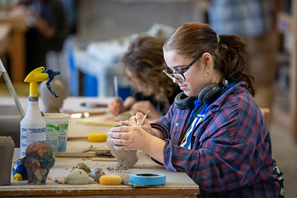 A SAW student carves into her ceramics project. 