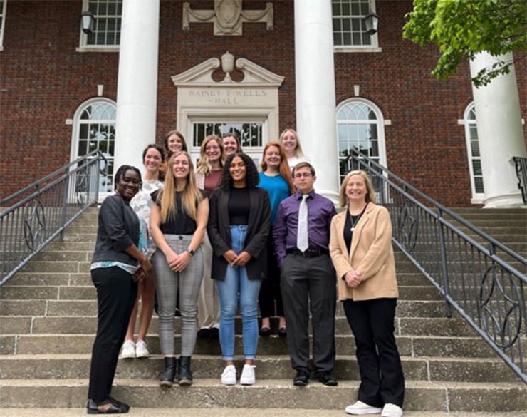 Group of student interns standing on steps in front of Wells Hall