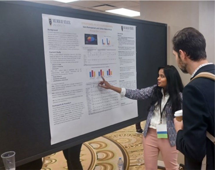 Student discussing research poster with onlooker