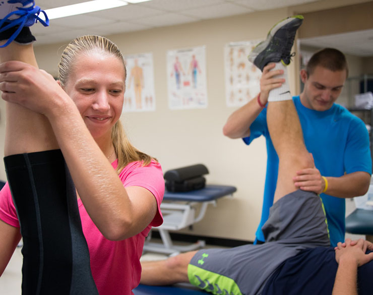 Two students help patients stretch