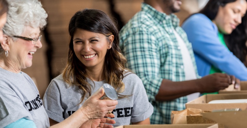 Volunteers packing canned foods into cardboard boxes