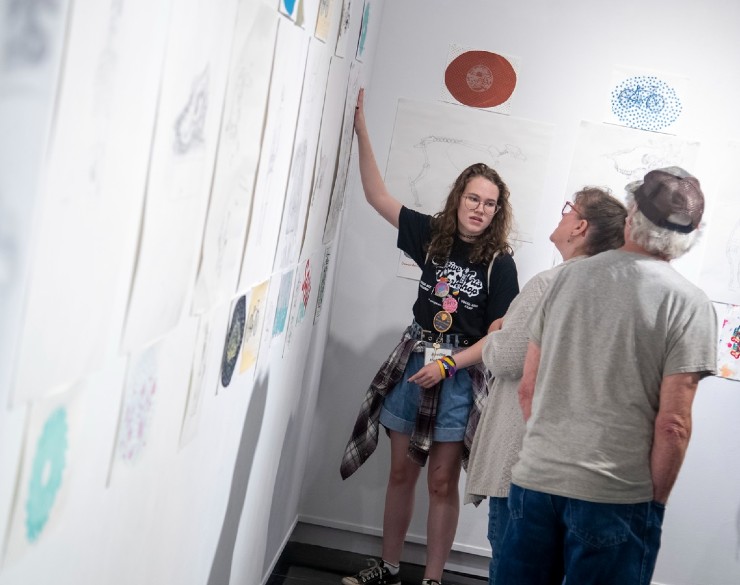 A SAW camper showing her family members art pieces hanging in Clara M. Eagle Art Gallery