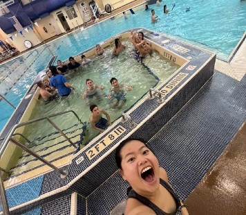 A RIMA camp counselor takes a selfie at the pool with RIMA campers in the background