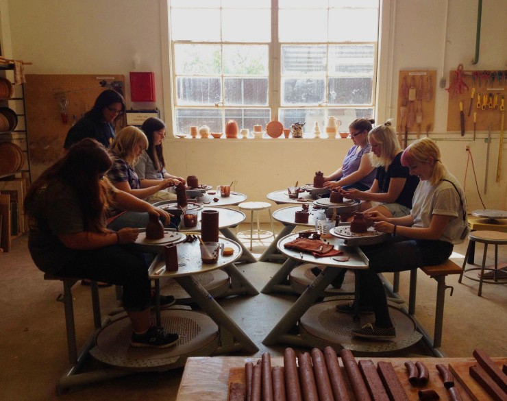 Six campers working at pottery wheels