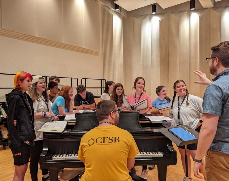 campers singing around piano