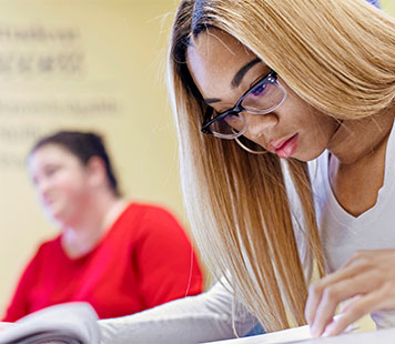 A student studies her textbook to learn more about admissions requirements. 