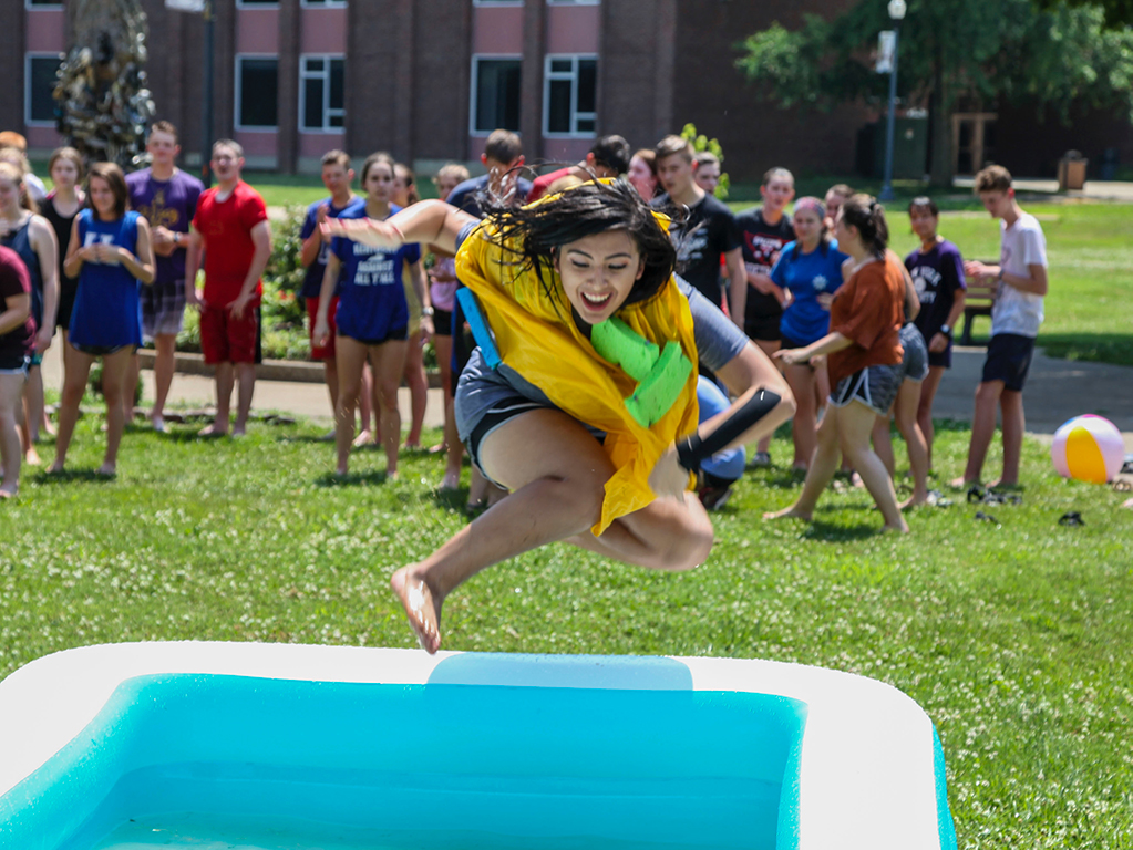 A student jumps into a pool during water olympics