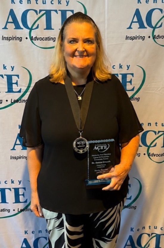 Dr. Donna Crouch in a black top and black and white pants holding her CTE award.