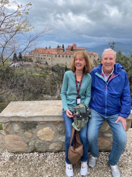 A woman on the left and a man on the right sit in front of a castle in the background