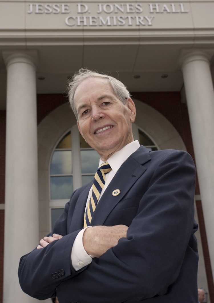 Dr. Jesse D. Jones in a navy blue suit and tie in front of his namesake chemistry hall.