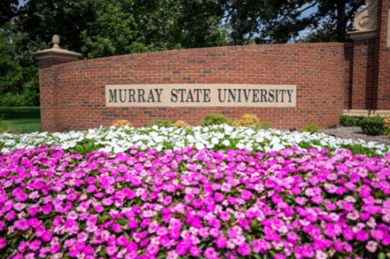 A brick Murray State University wall with pink and white flowers in the foreground.