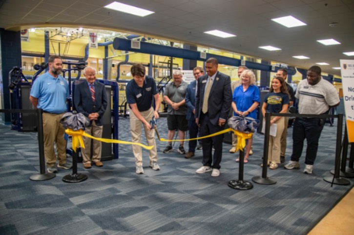 A group of people watch as a Murray State employee cuts a yellow ribbon inside the Wellness Center.