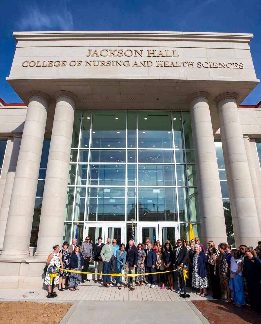 group of people cutting yellow ribbon with building in background
